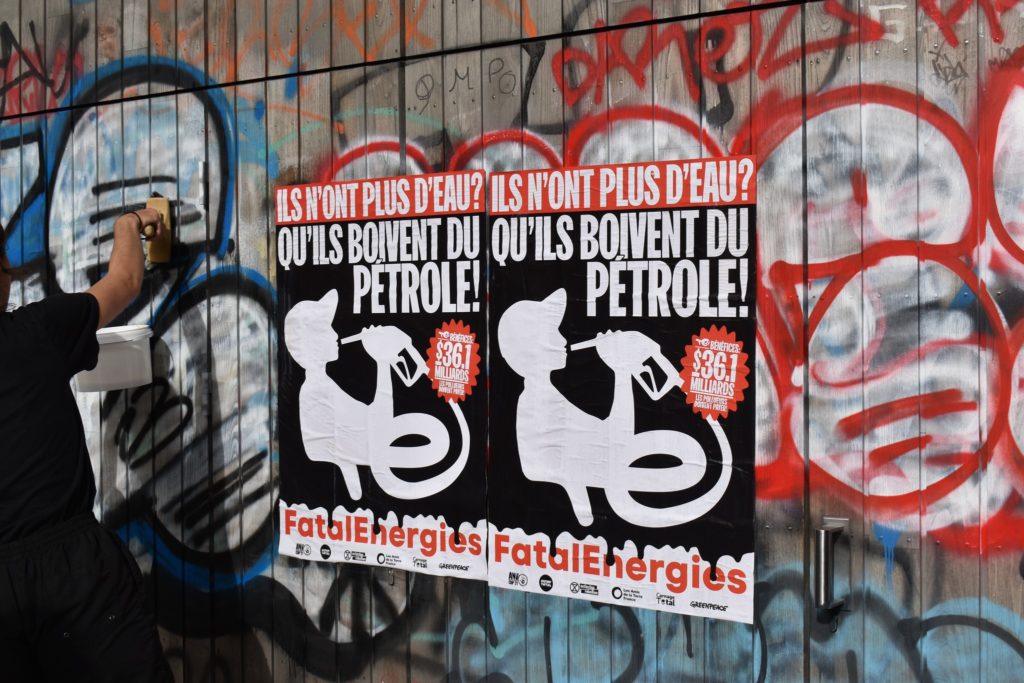 Photo d'un militant d'Alternatiba Rennes collant des affiches contre TotalEnergie