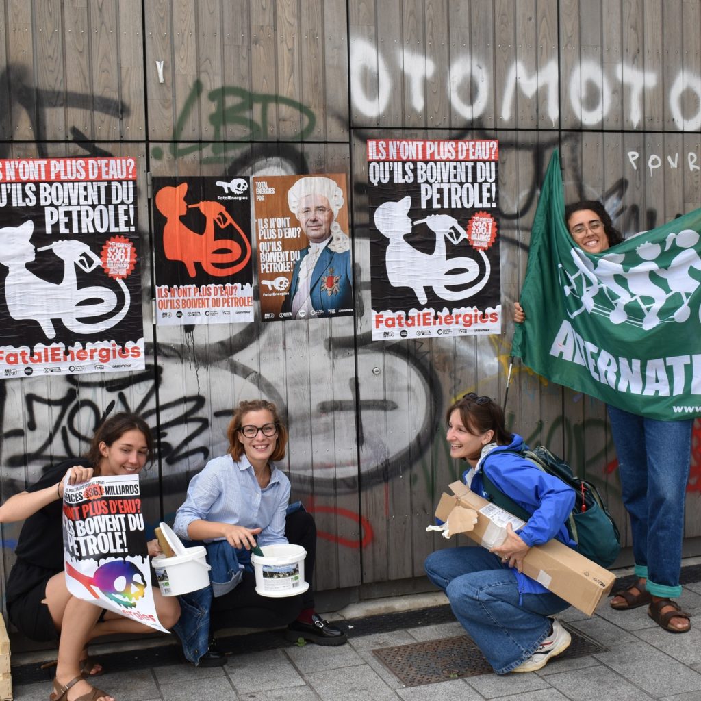 Photo de militantes d'Alternatiba Rennes devant des affiches collées contre TotalEnergies